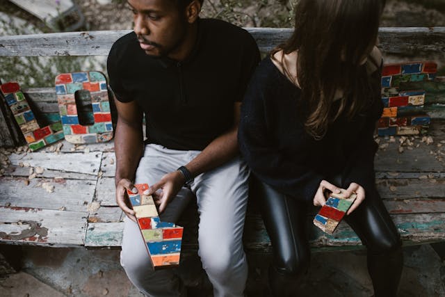 Couple in conflicts A couple sitting next to decor reading, 'love,' as they tear the letter 'v' apart