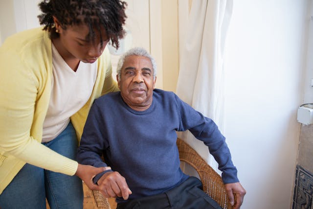 A young woman assisting her elder in sitting down