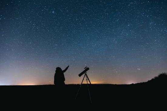 A person out under the starry sky with a telescope