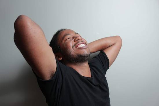 A debt-free man smiling with his arms raised and his hands folded behind his head
