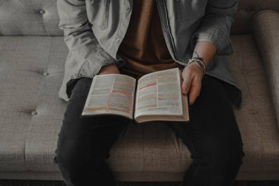 A man reading his marked Bible on a couch. Reading stories about others who faced discouragement can strengthen our faith.