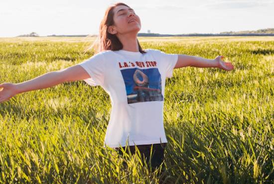 A woman in a field with her arms outstretched as she takes a deep breath of fresh air.