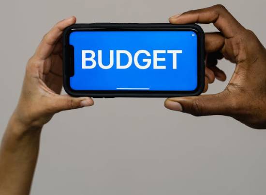 A phone with the word "BUDGET" on the screen, emphasizing the importance of budgeting.
