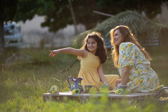 A mother playing with her daughter in the park as part of opportunities for bonding and enhancing communication.
