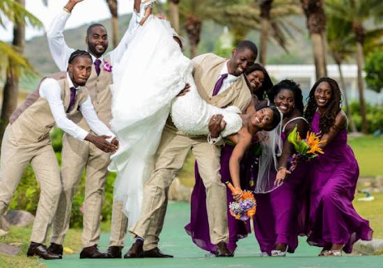 A groom, groomsmen, and bridesmaids all holding a bride
