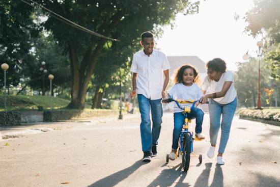 A man and his wife teaching their daughter how to ride a bike as an opportunity to share parental responsibilities.
