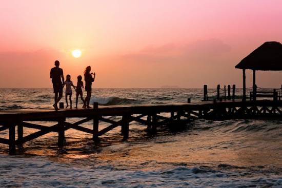 A family sighting a sunrise on a beach during their vacation.