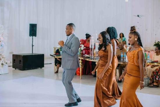 A groom and three bridesmaids dancing at the reception