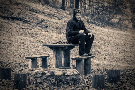 A man resting in a park as part of his bodily care routine.