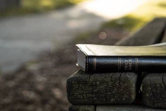 Black leather Bible on a wooden bench A Bible resting on a park bench