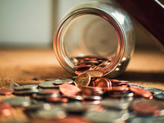 Coins pouring from a home banking jar.