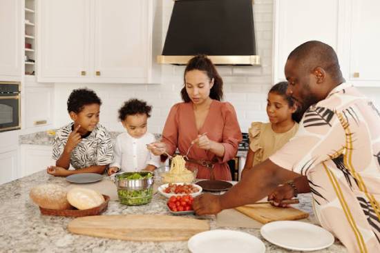 A family preparing dinner together with with dad and mum giving instructions.