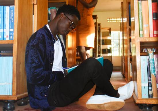 A man reading while sitting on the library's floor.