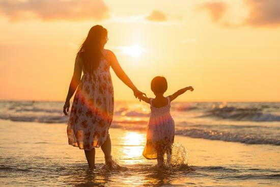 Mother and daughter walking on the beach to unwind and bond.