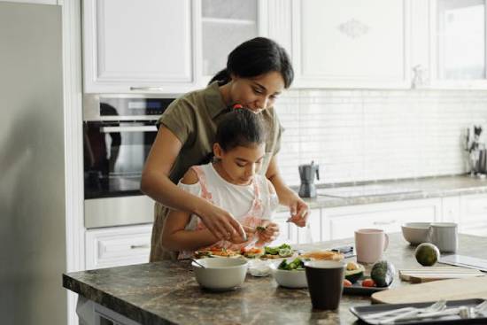 A health-conscious mother and daughter preparing avocado toast as part of their healthy living routine.