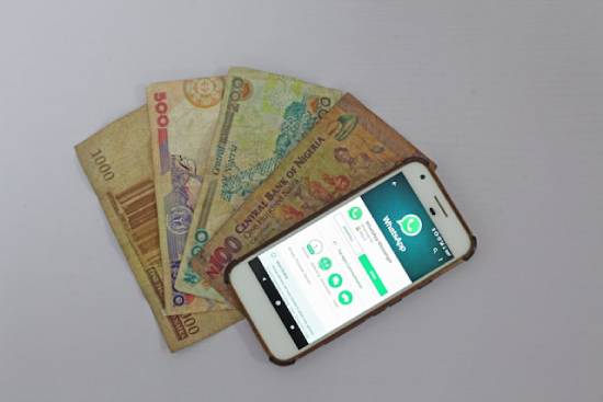 Banknotes arranged next to a phone opened to WhatsApp