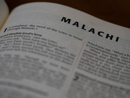 An open Bible showing the book of Malachi which has instructions on tithing.