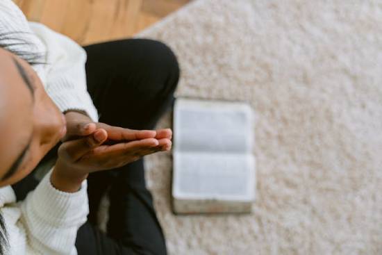 Woman praying in front of her open Bible A woman praying over her open Bible