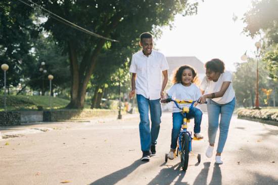 A couple training their daughter to ride a bike as part of their way of spending more time together.
