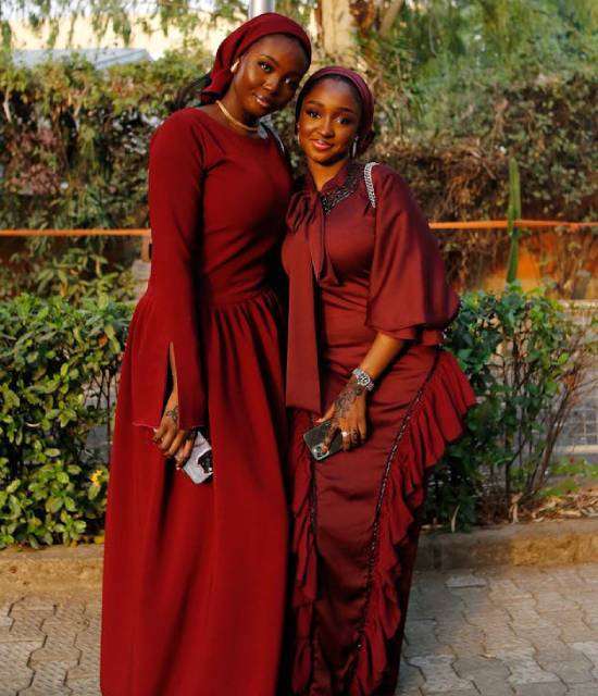 Two lady friends in elegant maroon dresses posing for a photoshoot.