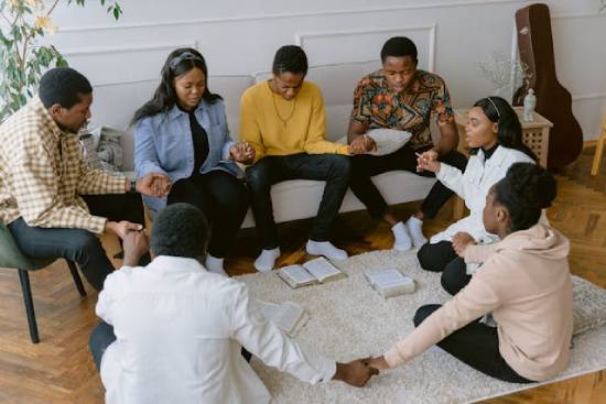 A family studying the Bible and praying together in the living room.