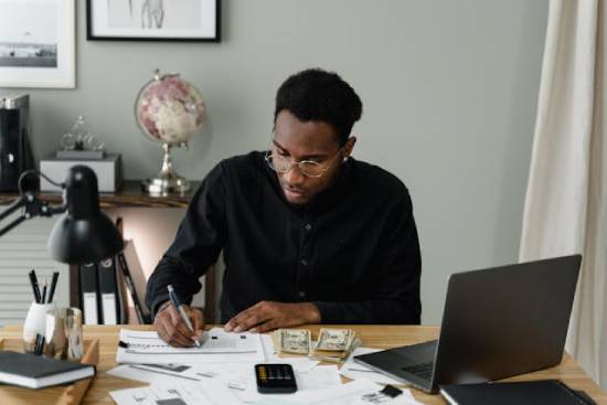 A man drafting a budget befr espending hs earnings to ensure proper financial decisions.