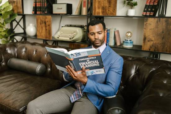 A amn sitting on a sofa reading about financial planning.