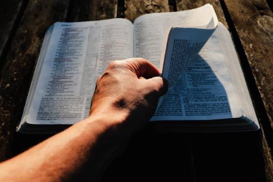 Hand Fliping the Pages of a Bible A human hand flipping the pages of an open Bible to find verses that address emotional anxiety.