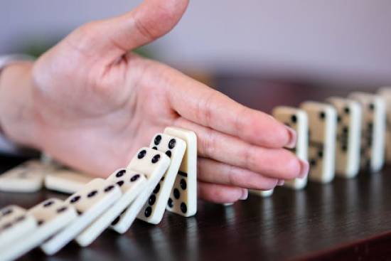 Blocking Dominoes A hand blocking dominoes representing barriers to decisions.