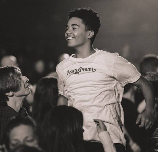 A Youth Celebrating Forgiveness A happy youth celebrating God's forgiveness during a spiritual meeting.