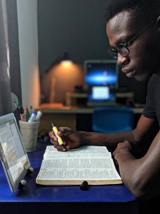A Man Studying the Bible A man keenly studying the bible and marking out texts with a highlighter.