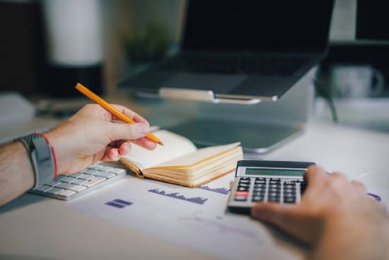 A person drafting a budget as part of their step to understand their financial obligations.