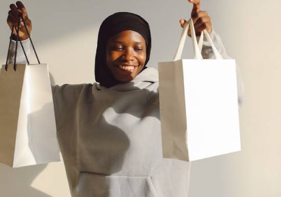 Woman Lifting Gift Bags A happy woman in a grey hoodie lifting two gift bags.
