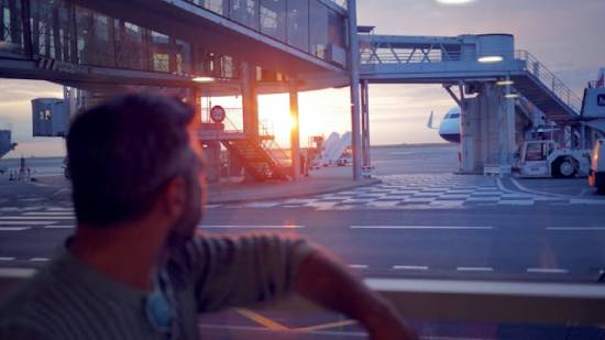 A man sitting on a bench and lost in deep thoughts in the Airport at sunset.