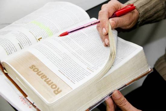 A person studying the book of Romans to understand God's role in their dreams and goals.