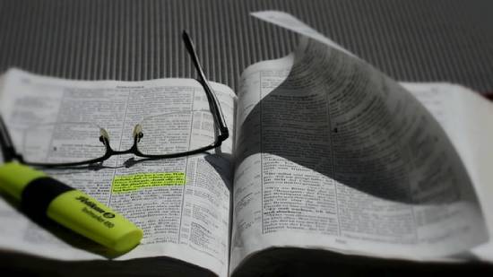 An open Bible with a luminous green highlighter and spectacles placed in it.