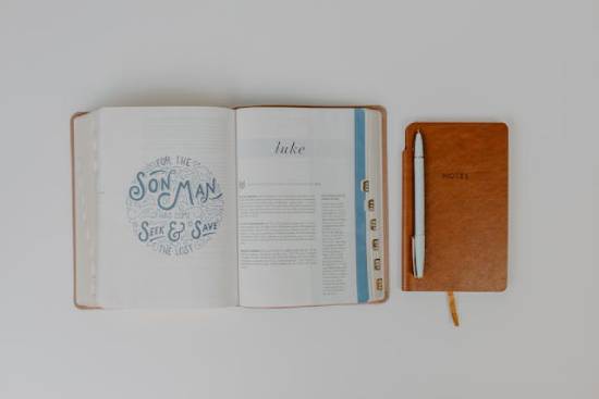 Bible and a Notebook An open Bible and notebook and pen for a deep study on biblical characters who discovered their purpose later in life.