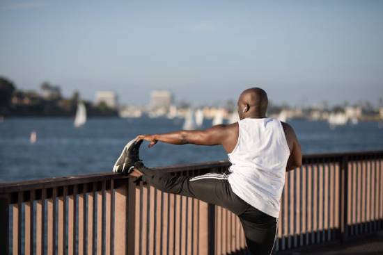 Bald Man Stretching A bald man stretching his legs over metallic rails by the seashore.