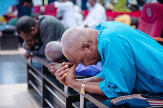 People Praying in a Church A group of people kneeling and praying in a church.