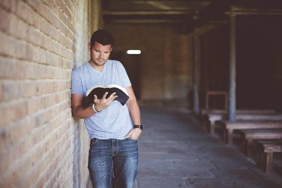 A Man Reading the Bible A man reading the Bible to find out what the Bible says about financial peace and decision-making.
