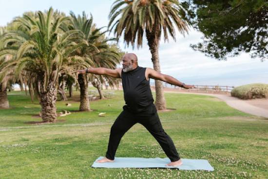 A Man Stretching in a Park A man dressed in black trauser and top stretching in a park by the seashore.