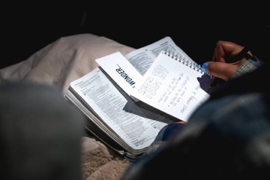 Personal Bible Study A person studying the Bible while making notes on a white notebook.
