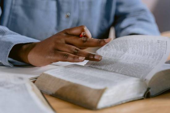 Personal Bible Study A person in a powder-blue long-sleeved shirt studying the Bible while holding a pencil.