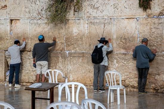 Four men praying for financial success against the wall.