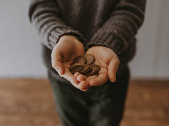 A Man Holding Copper Coins Hands of a man holding copper coins to be allocated to various budgetary needs.