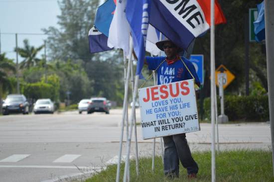A man in blue t-shirt holding a placard witnessing for Jesus Chrsit.