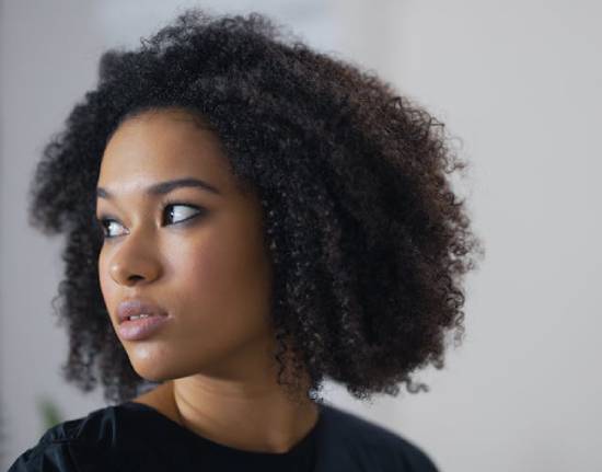 A thoughtful woman in black dress looking over her shoulder.