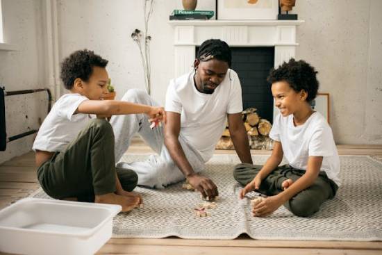 Father and Sons Playing at Home A father and sons in white tops playing on the floor at home.