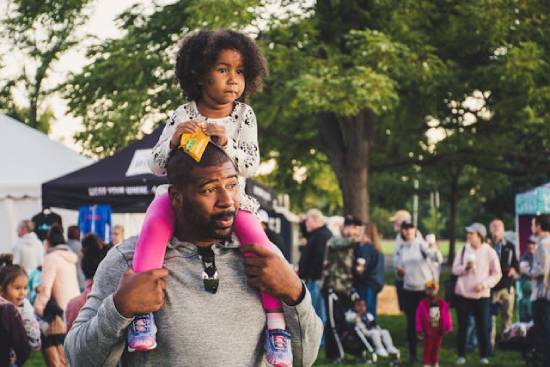 Family Fun Day A dad carrying a daughter on his shoulders during a fun activity with families and friends.