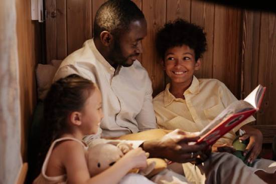 A smiling and happy dad reading bedtime stories to his children.